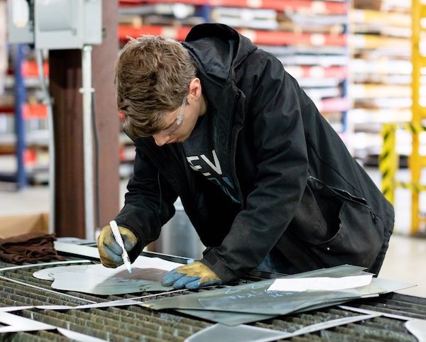 A US Duct employee sorting through laser cut sheet metal and preparing it for ductwork fabrication.