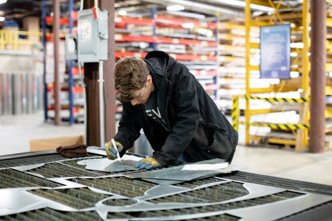 A US Duct employee marking laser-cut sheet metal pieces.