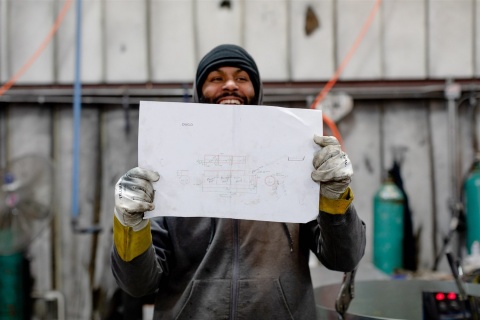 ductwork welder holding up a custom drawing